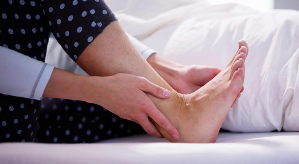 Someone holding their heel because it is in pain.